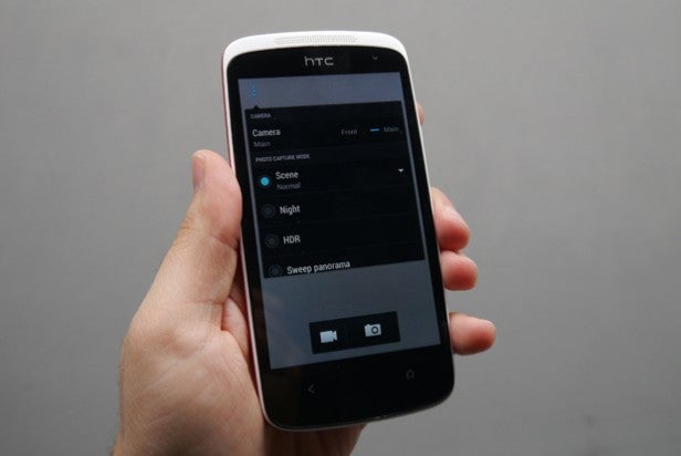 Hand holding smartphone displaying camera settings screen.