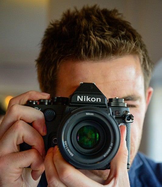 Man holding a Nikon camera up to his face.