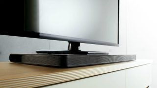 LG SoundPlate LAP340 under a flat-screen TV on a stand.
