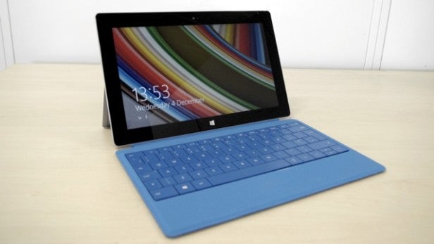Surface tablet with attached blue keyboard cover on desk.