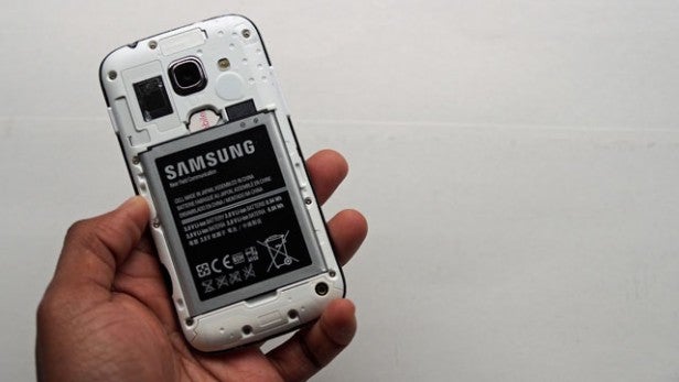 Hand holding a Samsung phone with its back cover removed revealing the battery.