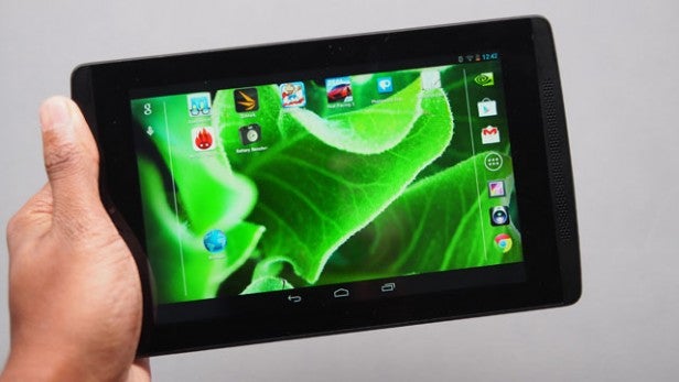 Hand holding a tablet with a green leaf wallpaper on screen.