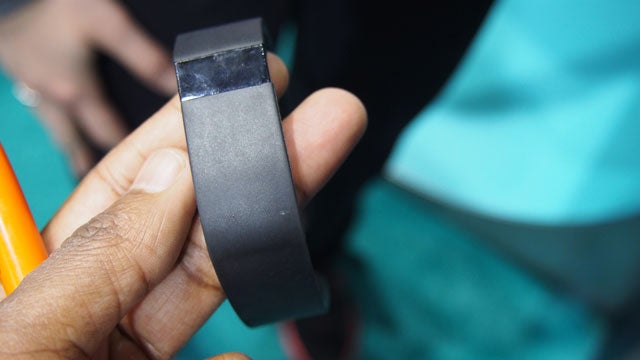 Hand holding a Fitbit Force fitness tracker.