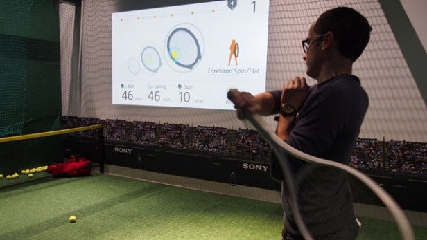 Person playing tennis with Sony sensor data projected on screen.Person analyzing tennis performance data displayed on screen.