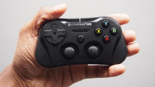 Hand holding a SteelSeries Stratus gaming controller.