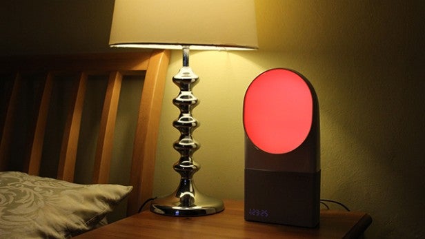 Withings Aura sleep aid device illuminated red on a nightstand.