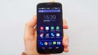 Hand holding a Motorola Moto X displaying home screen.