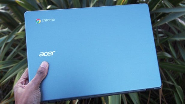 Hand holding an Acer Chromebook against foliage background
