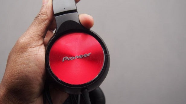 Hand holding Pioneer SE-MJ532-R red and black headphones.
