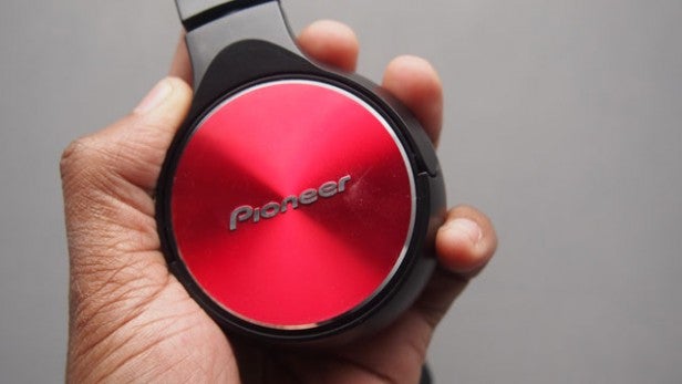 Hand holding Pioneer SE-MJ532-R red and black headphones.
