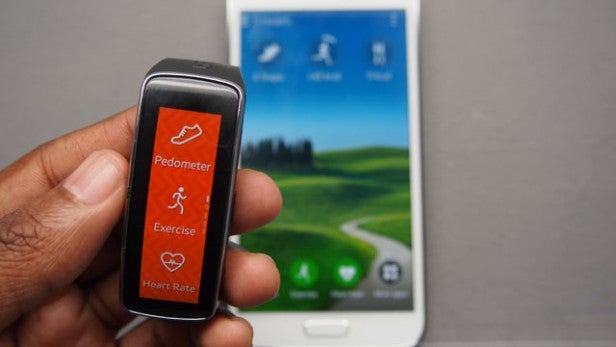 Hand holding a fitness tracker with pedometer and heart rate features.