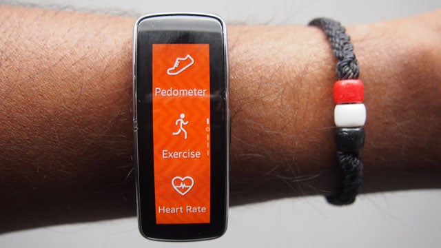 Samsung Gear Fit on wrist displaying pedometer and heart rate.