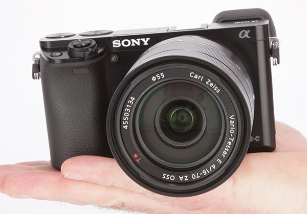 Sony A6000 camera held in hand showing lens and controls.