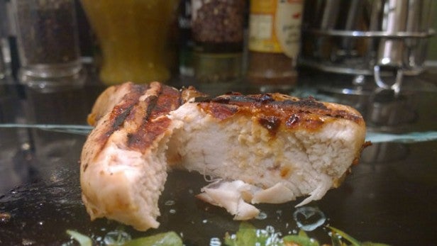 Grilled chicken breast with a golden-brown crust on a plate.