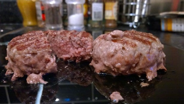 Two cooked hamburgers with one cut open showing doneness.