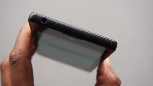 Hand holding smartphone showcasing its top edge and ports