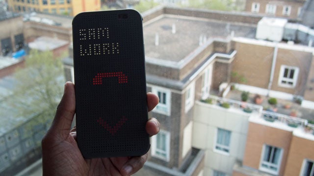 Hand holding HTC Dot View case displaying time and notifications