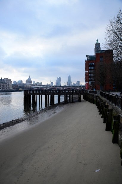 Riverbank with pier and urban skyline in the background