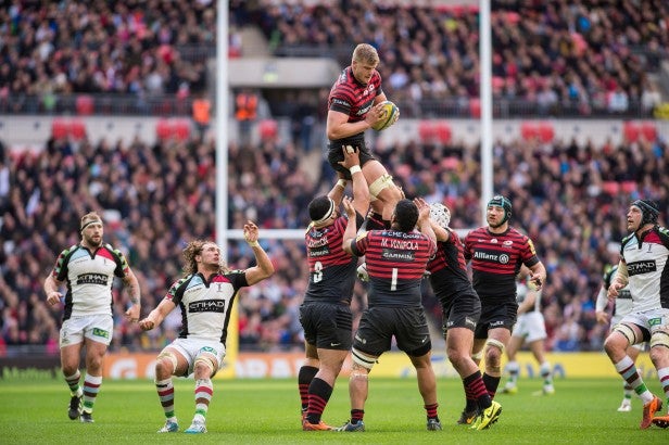 Rugby players during line-out play in a packed stadium.