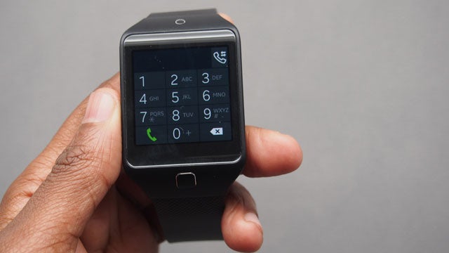 Hand holding a Samsung Gear 2 Neo smartwatch displaying keypad.