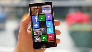 Hand holding a Nokia Lumia 930 displaying apps on screen.