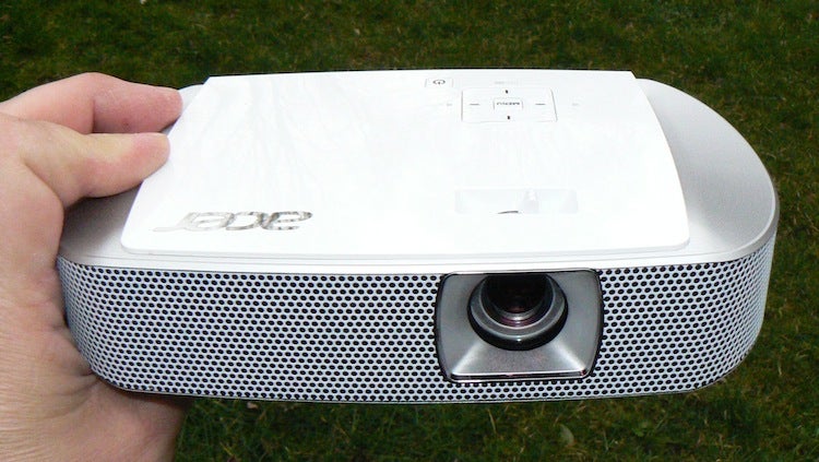 Hand holding Acer K137 LED portable projector outdoors