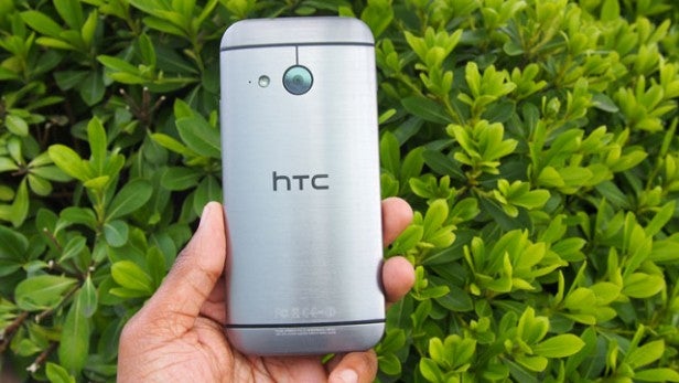 Hand holding HTC smartphone with metallic back.