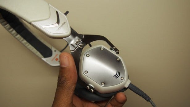 Hand holding V-Moda XS on-ear headphone with silver cups
