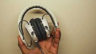 Hand holding a pair of V-Moda XS headphones.