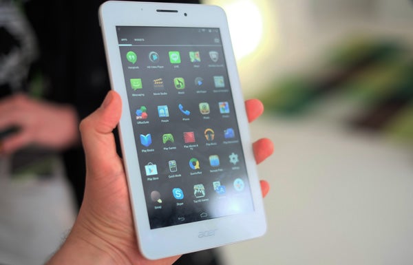 Hand holding an Acer Iconia Tab 7 displaying apps.