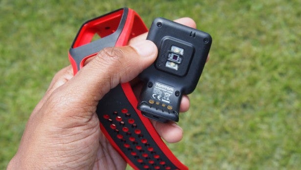 Hand holding a red and black electronic device outdoors.