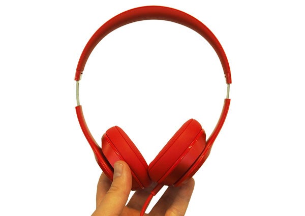 Hand holding red Beats Solo 2 headphones against white background.Beats Solo 2 headphones in various colors displayed in a row.