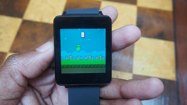 LG G Watch displaying game on screen, held in hand.