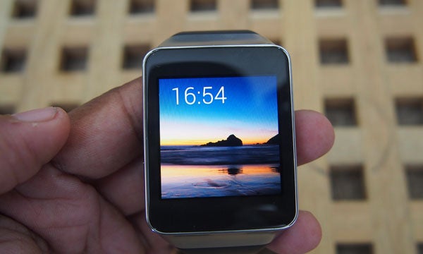 Hand holding a Samsung Gear Live smartwatch displaying the time