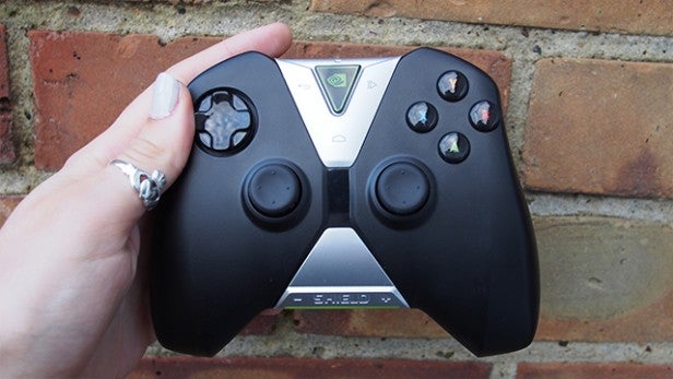 Hand holding a Shield gaming controller against a brick wall.