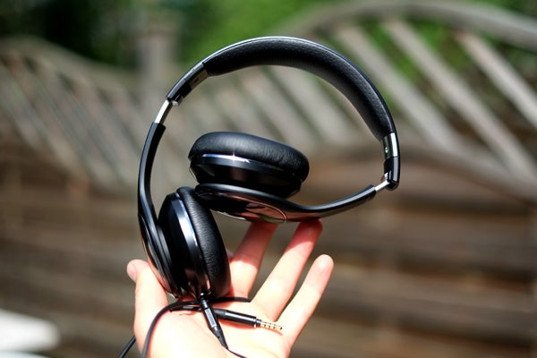 Samsung Level On headphones held in a person's hand outdoors.
