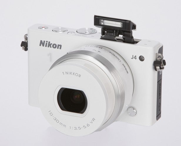 Nikon 1 J4 camera with flash popped up on white background.