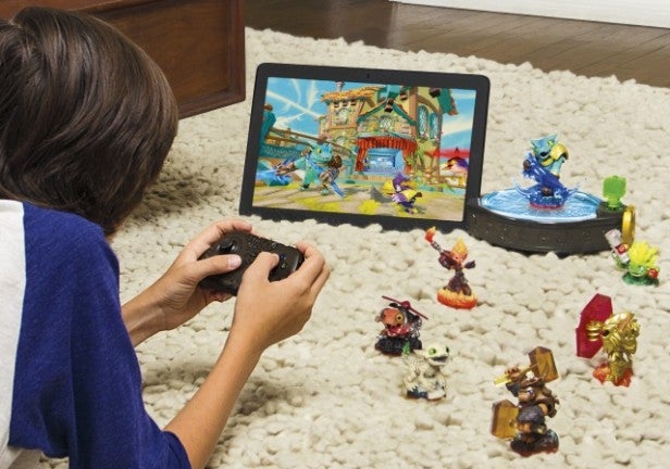 Child plays Skylanders Trap Team on tablet with figures.