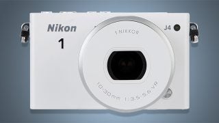 Nikon 1 J4 camera with 10-30mm lens on gray background.