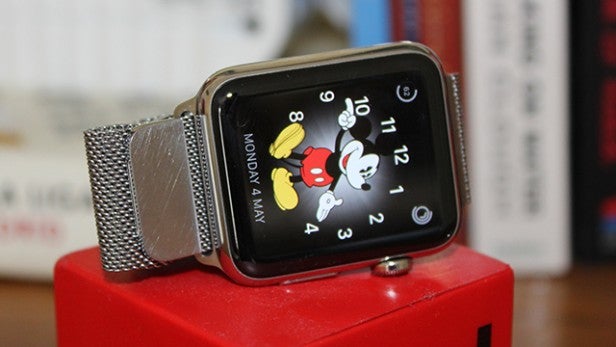 Apple Watch with Mickey Mouse watch face on red stand.