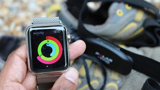 Smartwatch displaying activity tracking rings with fitness gear in background.