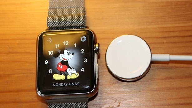 Smartwatch with Mickey Mouse display connected to its charger.