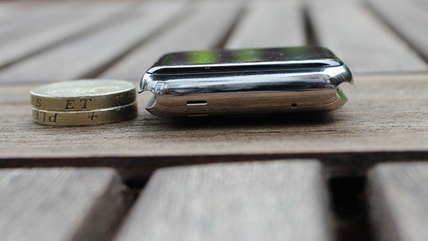 Apple Watch beside a coin on a wooden surface.