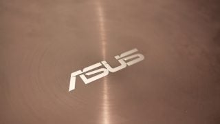 Close-up of ASUS logo on brushed metal surface.