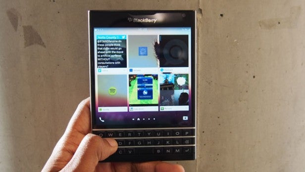 Hand holding a BlackBerry Passport smartphone displaying screen content