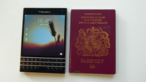 BlackBerry Passport smartphone next to a UK passport for size comparison.