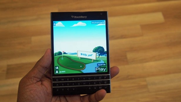 Hand holding a BlackBerry smartphone displaying an app screen.