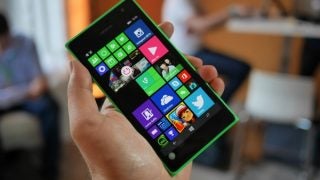 Hand holding a Nokia Lumia 735 with colorful display screen.