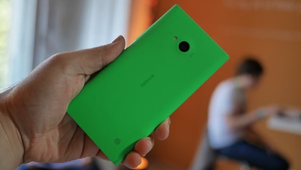 Hand holding a green Nokia Lumia 735 smartphone.