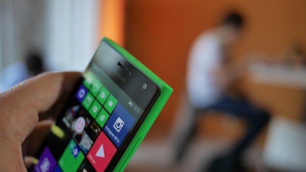 Hand holding a Nokia Lumia 735 with colorful display.
